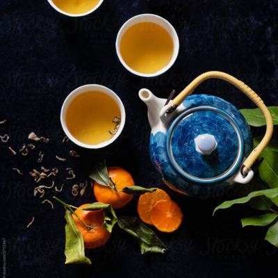 blue tea pot with tea cup and oranges.